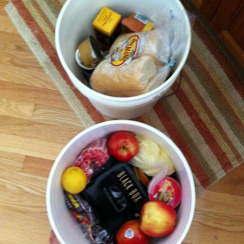 Food buckets with essentials: fruit, cookies, local bread, and plenty of wine.